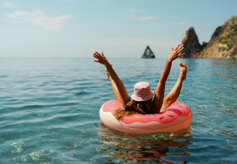 Woman floating on lake in pink donut tube